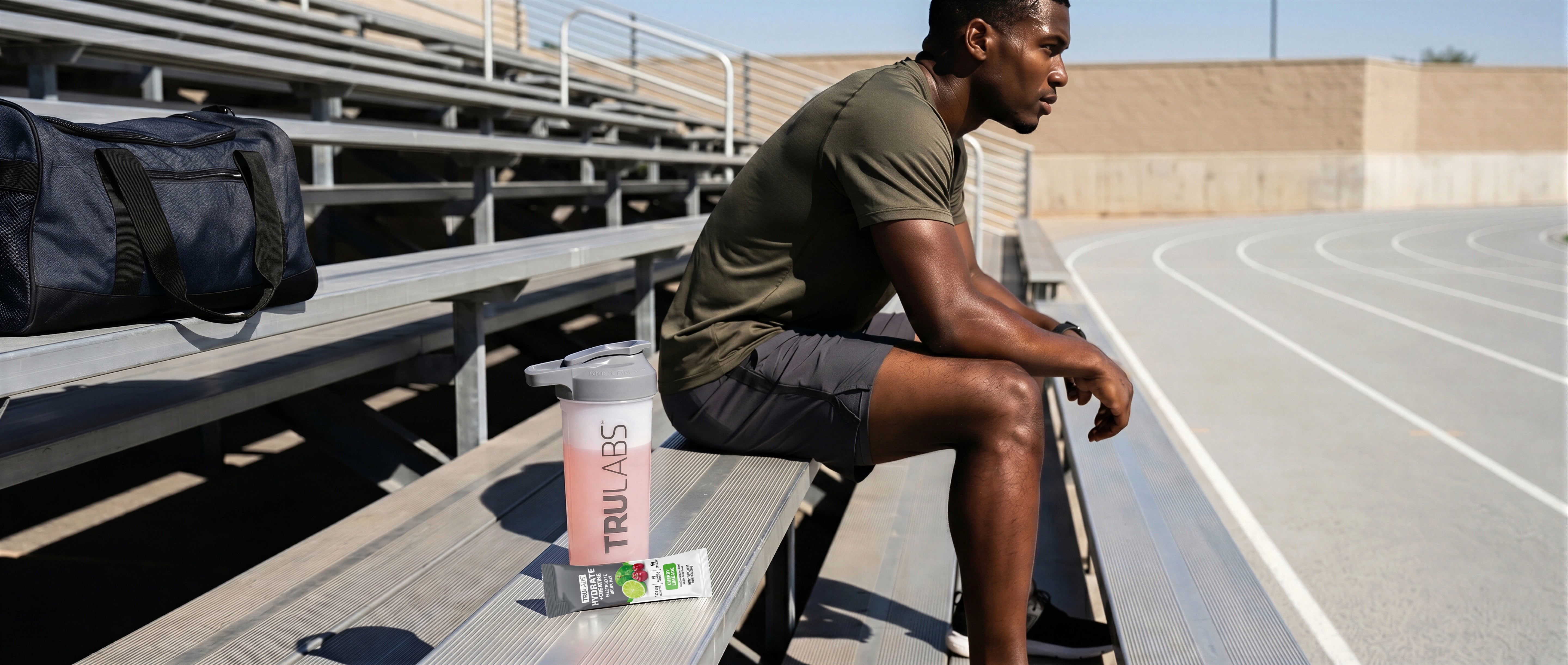 Man sitting on bleachers with a sports bottle and snacks, outdoors.